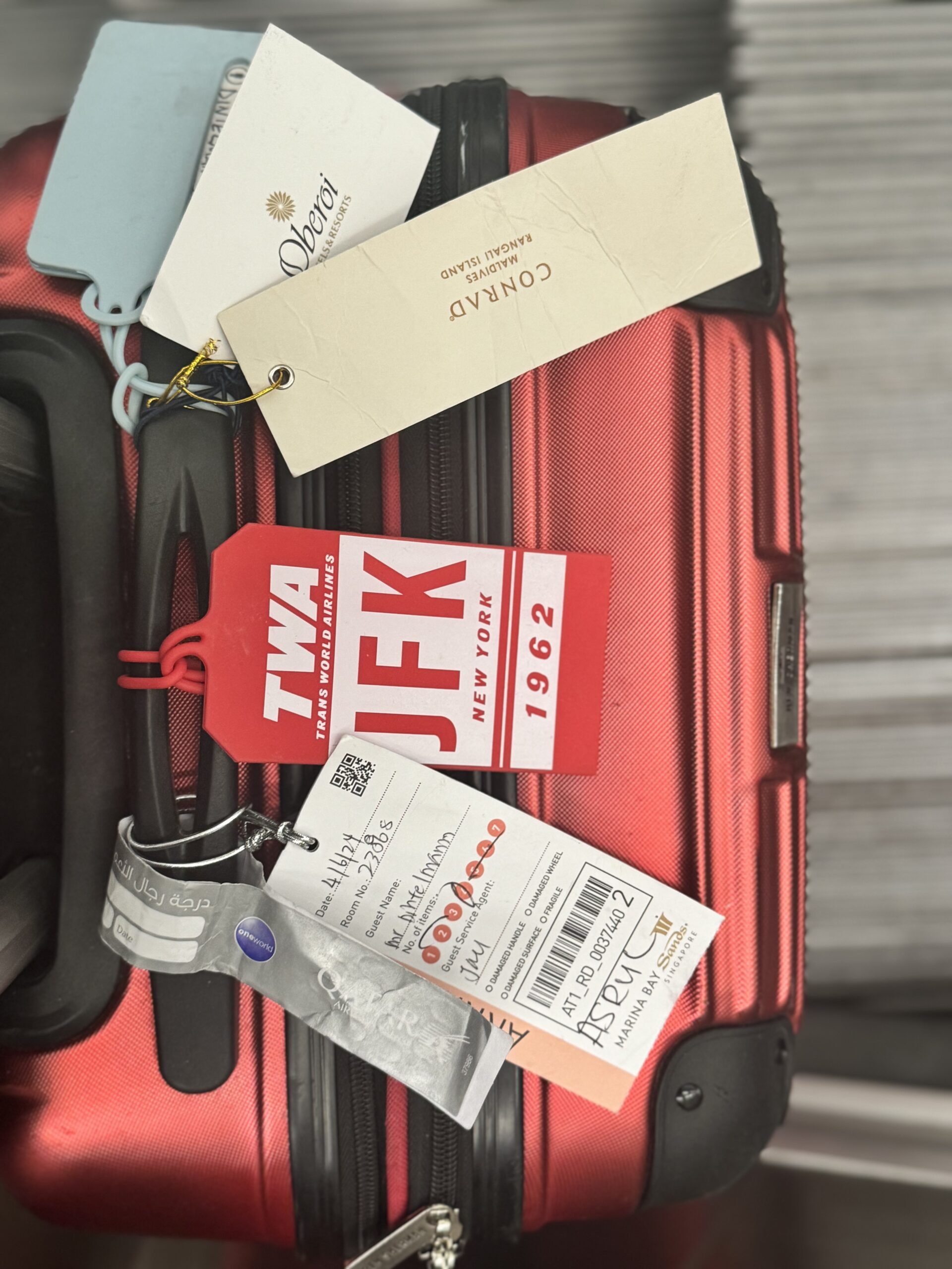 Red suitcase with luggage tags from different hotels.