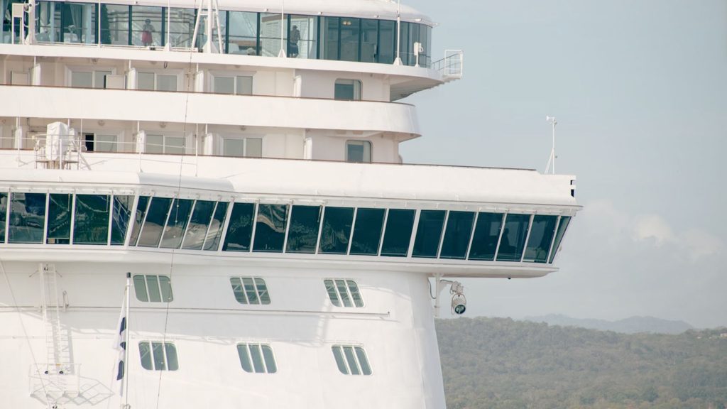 Small expedition cruise ship approaching a remote Pacific island, representing travel to Micronesia