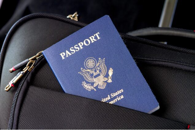 USA Passport sticking out of a black briefcase.